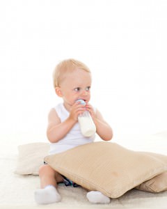Baby boy drinks milk from bottle.